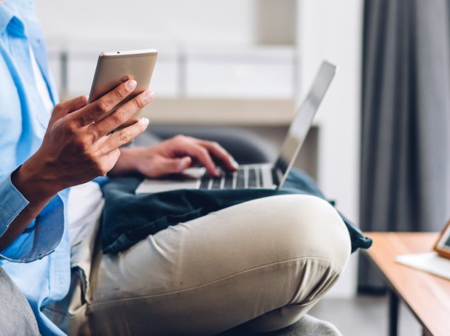uomo sul divano a gambe conserte che lavora con il computer sulle gambe