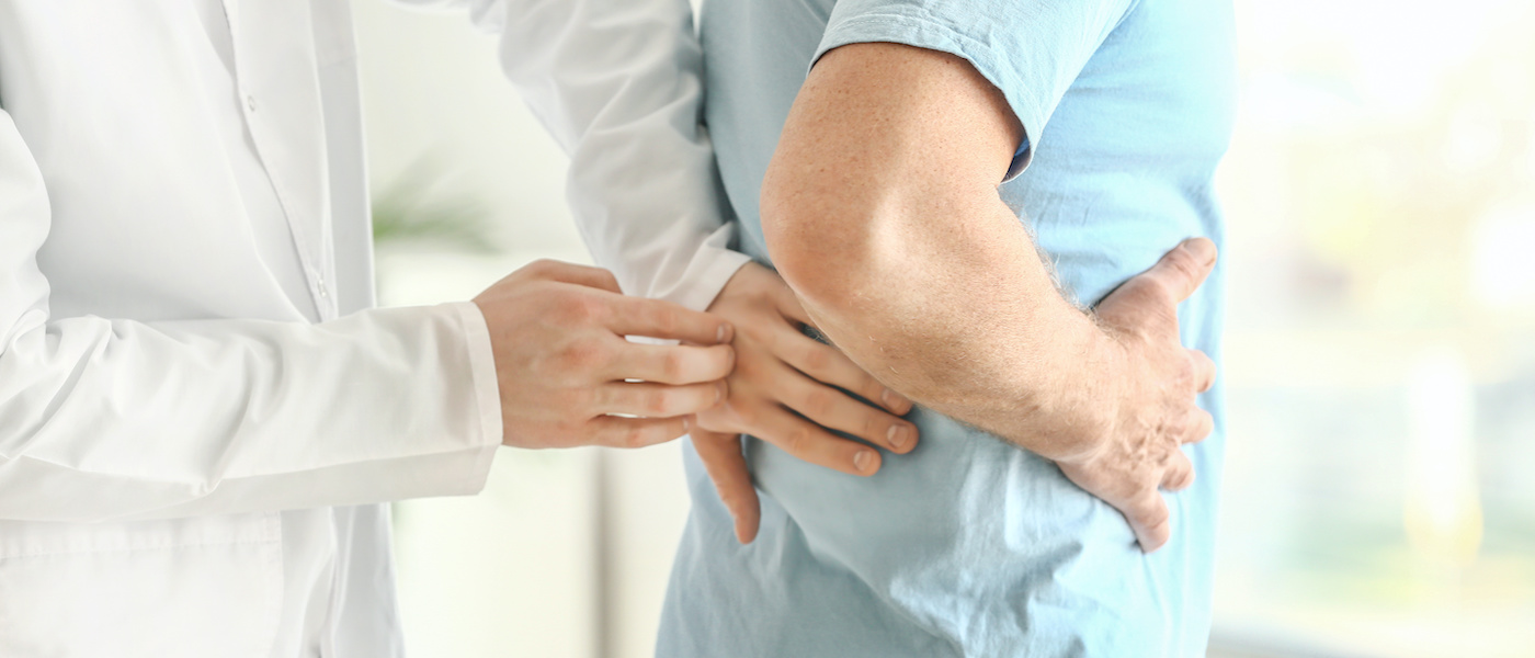 Urologist examining male patient in clinic