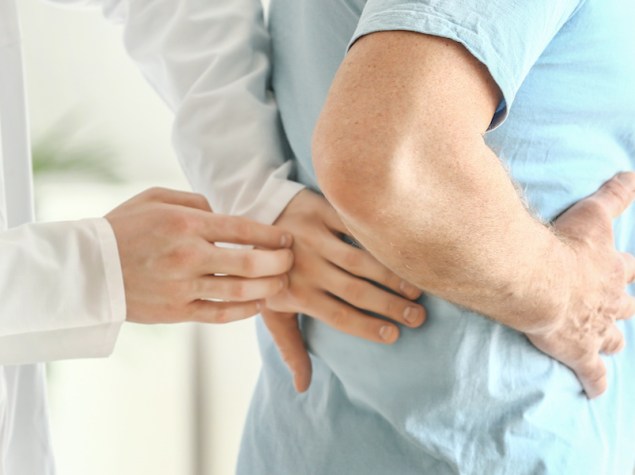 Urologist examining male patient in clinic
