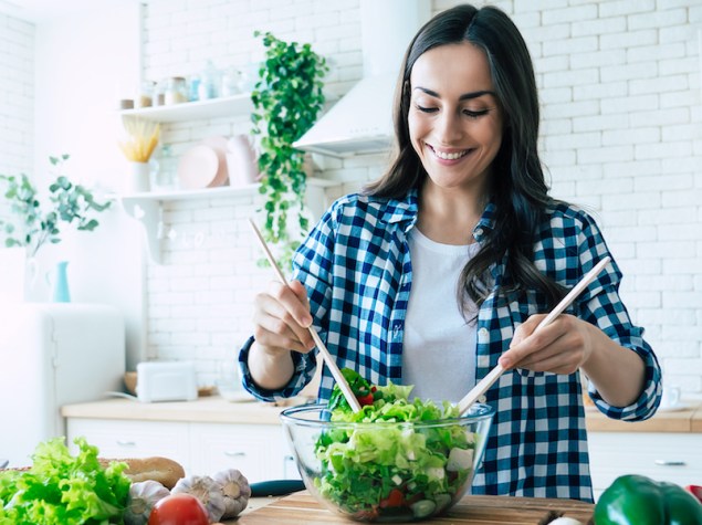 ragazza che mischia l'insalata in un'insalatiera