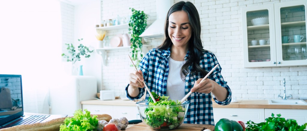 ragazza che mischia l'insalata in un'insalatiera