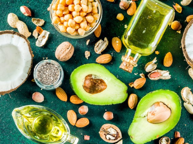 vari alimenti che contengono omega-3, quali avocado olio di oliva e mandorle, sparpagliati su un tavolo