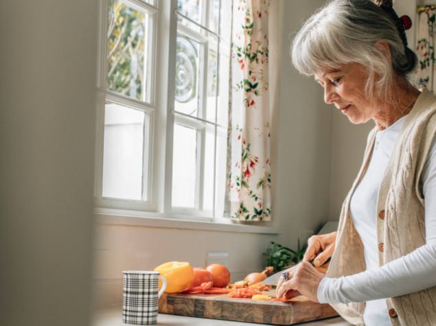 signora anziana che condisce una ciotola con insalata