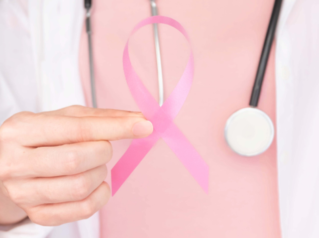 dottoressa che tiene in mano un fiocco rosa, simbolo della lotta al tumore al seno