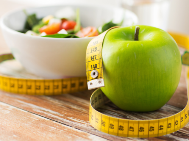 Mela, ciotola di verdura e un centimetro su un tavolo