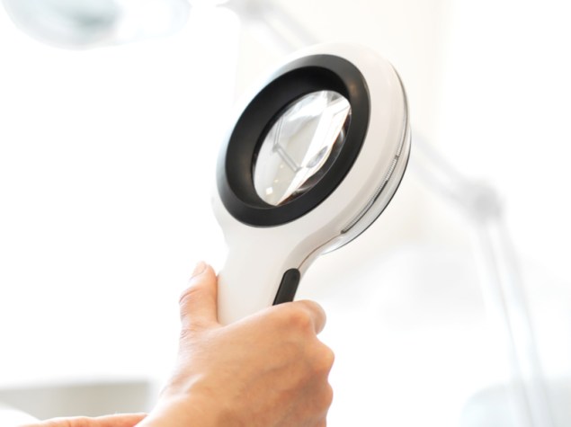 dottore con dermoscopio su sfondo bianco