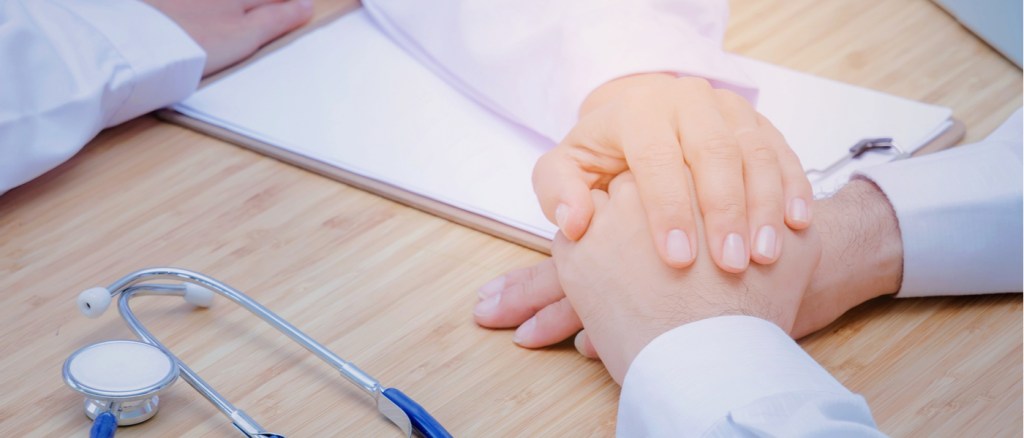 mano del dottore che tiene la mano di una paziente