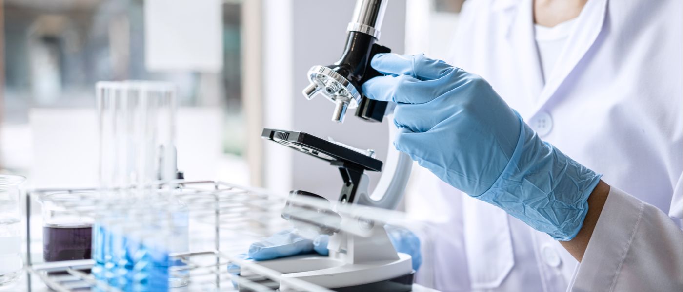 ricercatore scientifico che osserva un vetrino nel microscopio