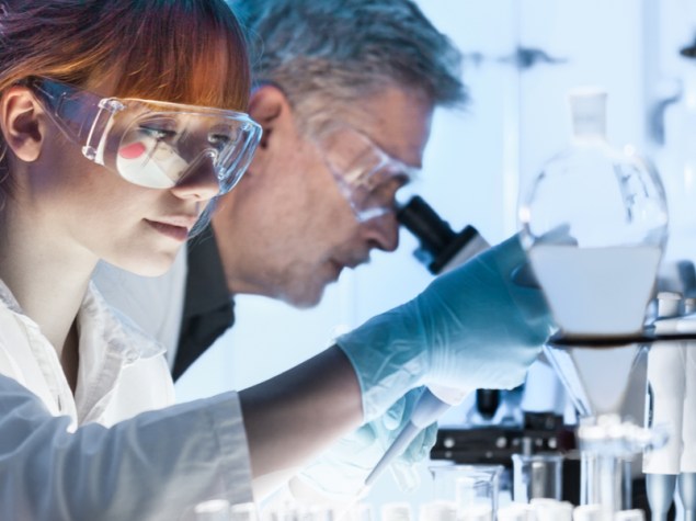 ricercatori in camice che osservano i vetrini di un microscopio