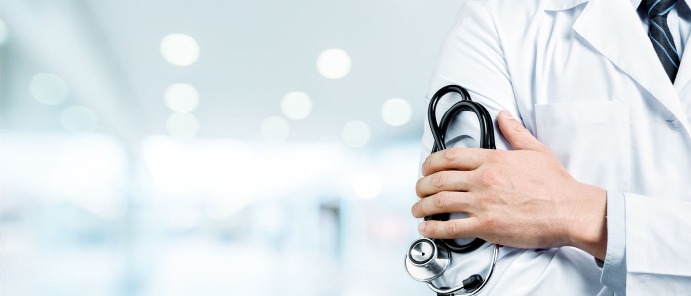 dottore con camice bianco che tiene stetoscopio in mano