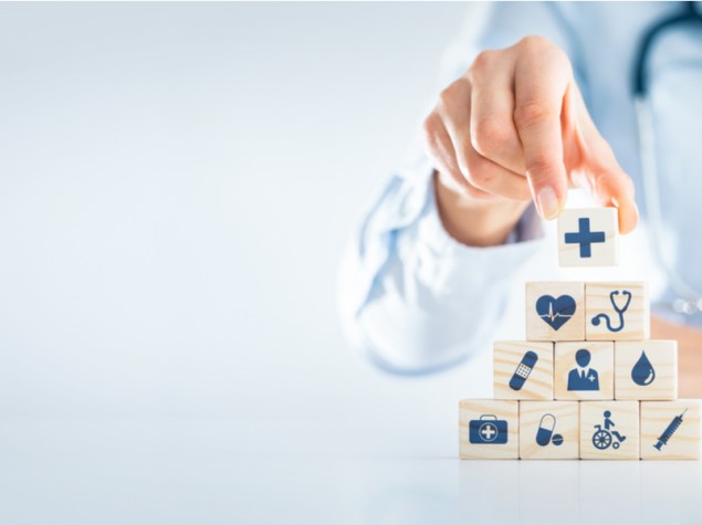 dottore che costruisce una piramide di cubi con disegni inerenti alla medicina