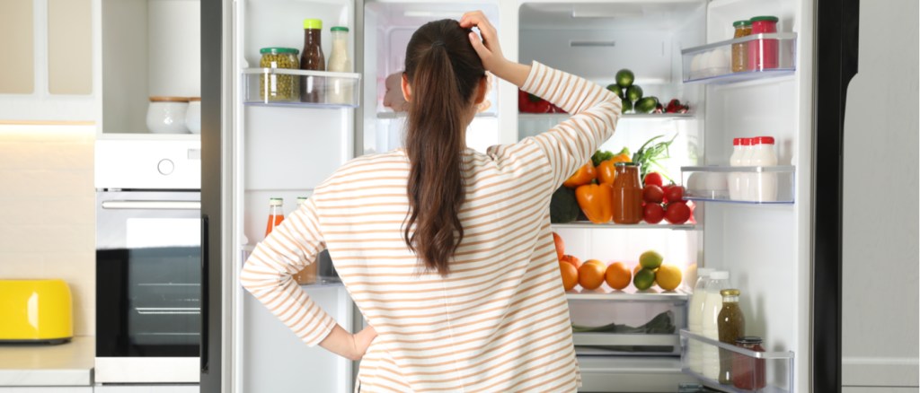 donna che guarda nel frigo dubbiosa su quali alimenti mangiare