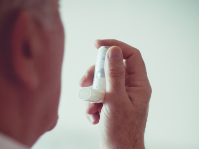 foto di un uomo di spalle che avvicina un inalatore per asma verso il volto