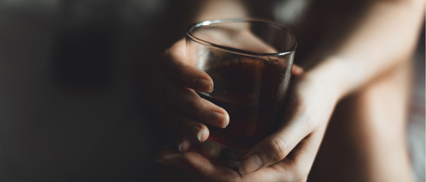 nell'ombra spuntano due mani che tengono bicchiere di bevanda alcolica