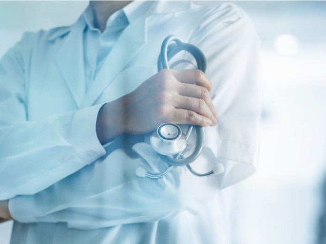 dottore a mezzo busto con le braccia conserte che tiene lo stetoscopio con la mano sinistra