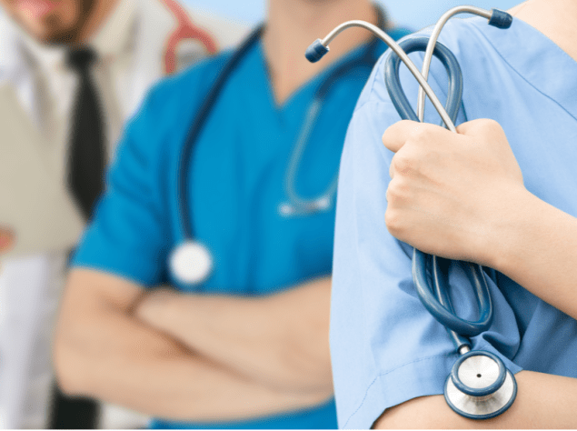 tre medici ripresi dalle spalle alla vita in fila con i loro stetoscopi