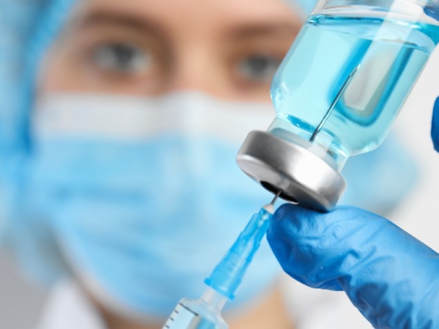 dottore che preleva riempie una siringa dal flacone di un farmaco