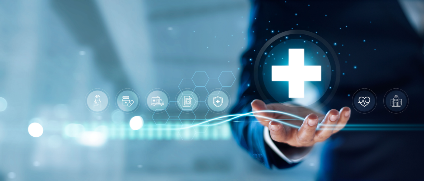 uomo in giacca e cravatta che tiene sul palmo della mano l'ologramma di una croce sanitaria