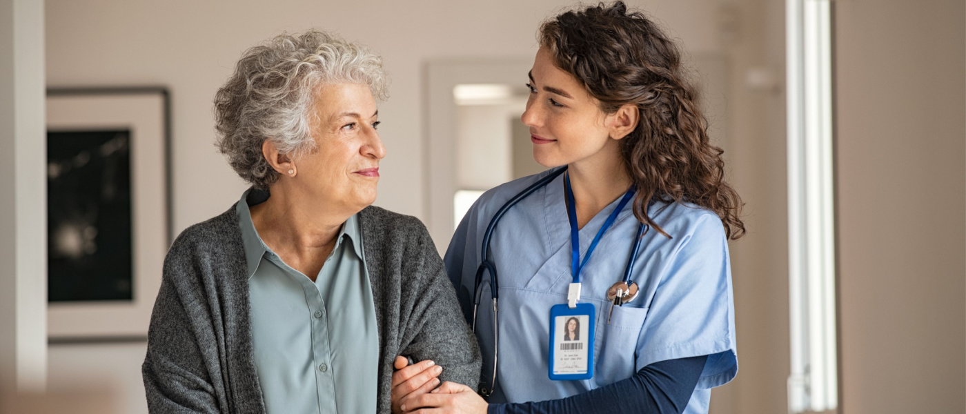 infermiera che porta sotto braccio una paziente anziana