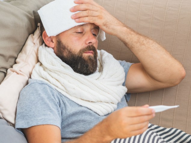 uomo sdraiato divano misura febbre termometro