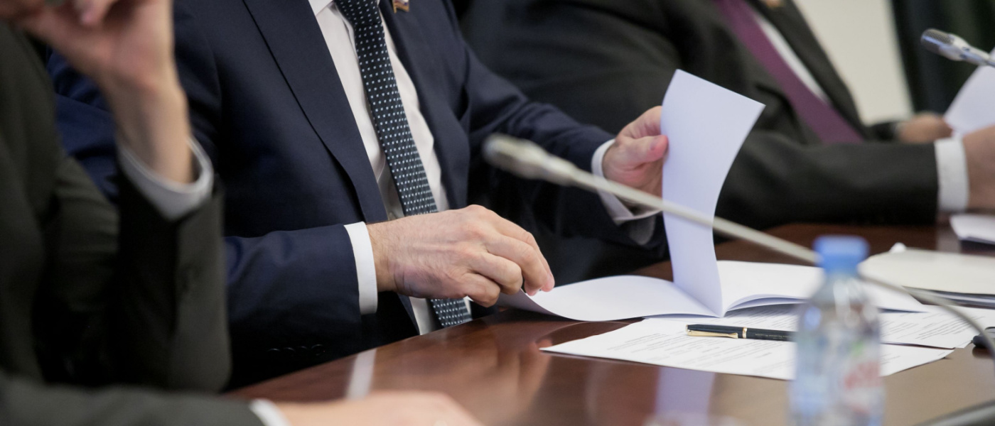 uomo giacca cravatta sfoglia dossier tavolo