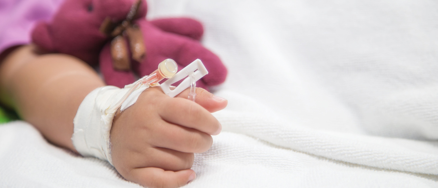bambina senza volta sul letto di ospedale con flebo che tiene orsetto rosa