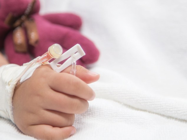 bambina senza volta sul letto di ospedale con flebo che tiene orsetto rosa