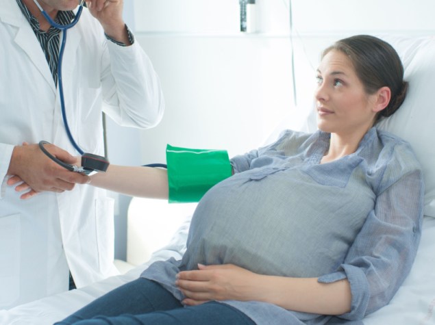 Doctor taking pregnant woman's blood pressure