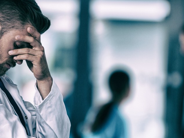 giovane medico stressato appoggiato muro mano sul viso