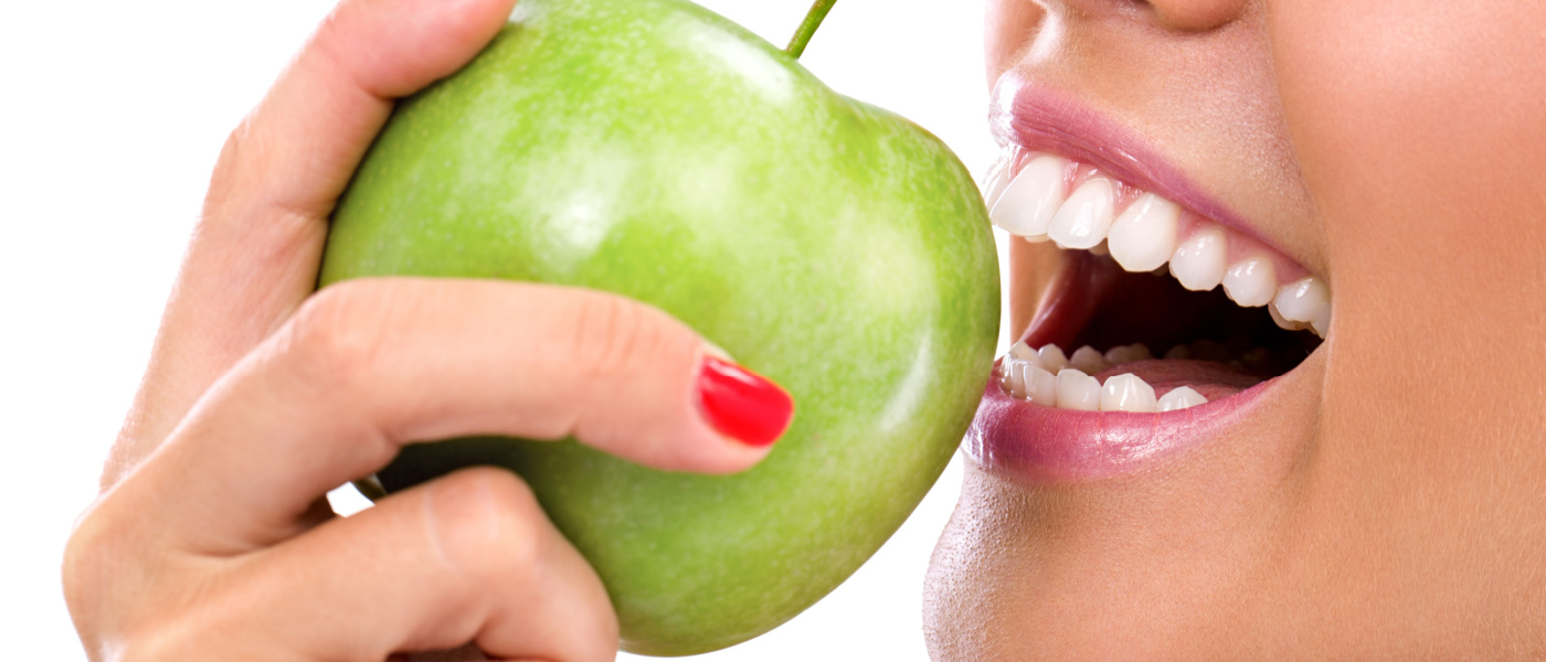 Primo piano del volto di una donna che mangia una mela verde, isolato su sfondo bianco