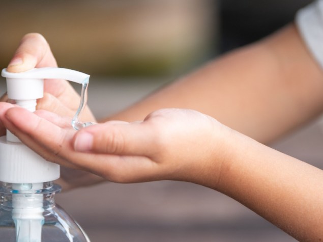 Mani di bambino che usano il gel igienizzante per le mani, Dispenser a pompa, Focus selezionato