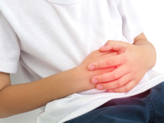 Bambino con mal di stomaco su sfondo bianco. Concetto di salute. Foto ravvicinata, sfocata.