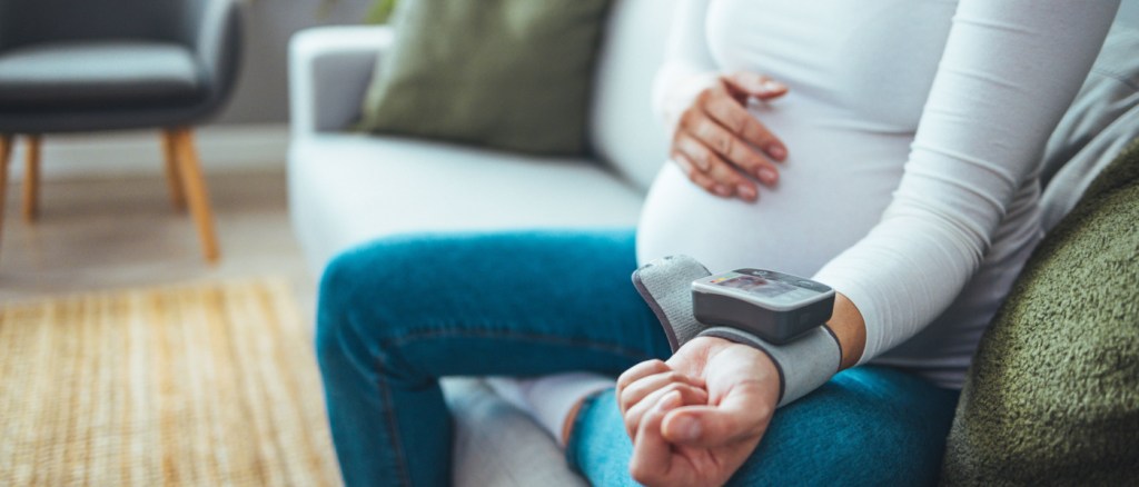Donna incinta misura la pressione sanguigna con un tonometro elettronico. Ipertensione
