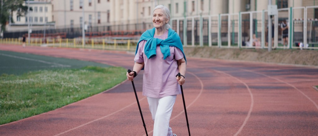 Donna anziana pratica nordic walk. Anziana signora scandinava pole hike stadio. Nonna sport allenamento Europa. Stile di vita delle donne in salute.