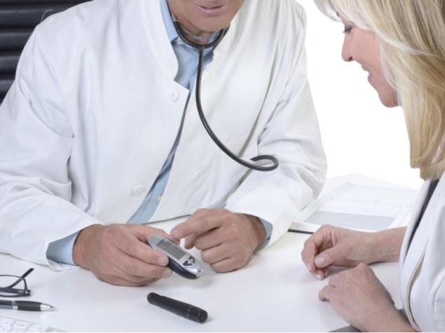 medico parla ad un paziente mostrando un misuratore della glicemia