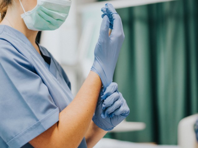 Infermiera senza volta si mette un guanto