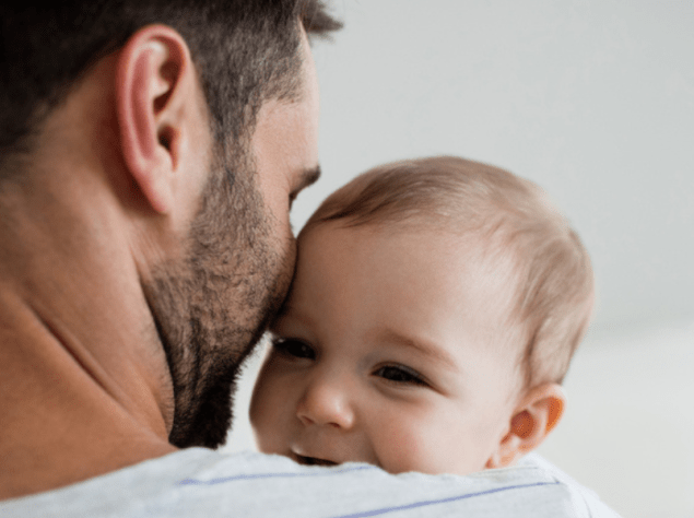 padre di spalle che tiene in braccio suo figlio