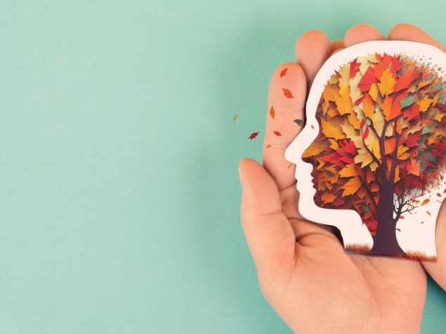 mani che tengono l'immagine di una testa umana composta da foglie marroni e gialle