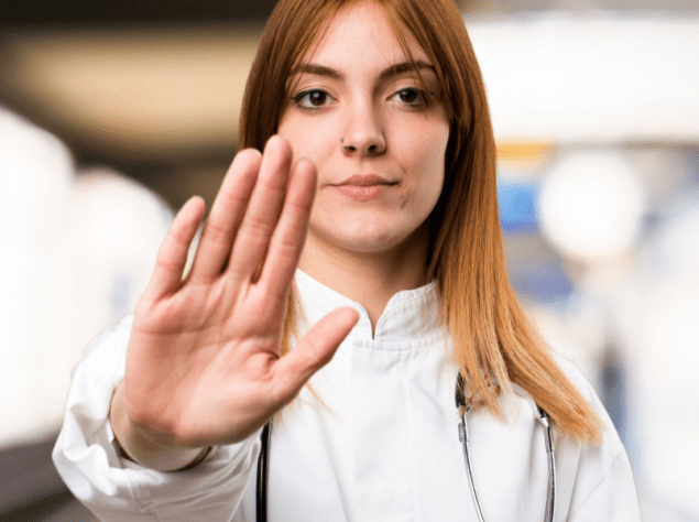 operatore sanitario che stende il braccio di fronte a se in segno di blocco