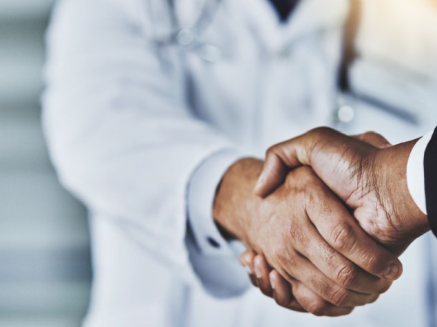 stretta di mano tra dottore e politico in giacca e camicia