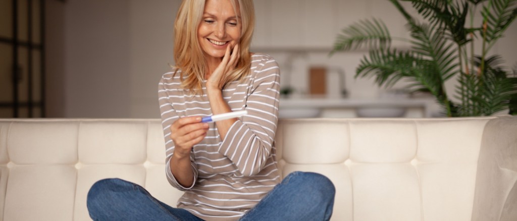 Donna over 40 felice guardando il test di gravidanza