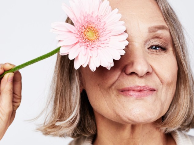 Donna anziana con un fiore davanti l'occhio
