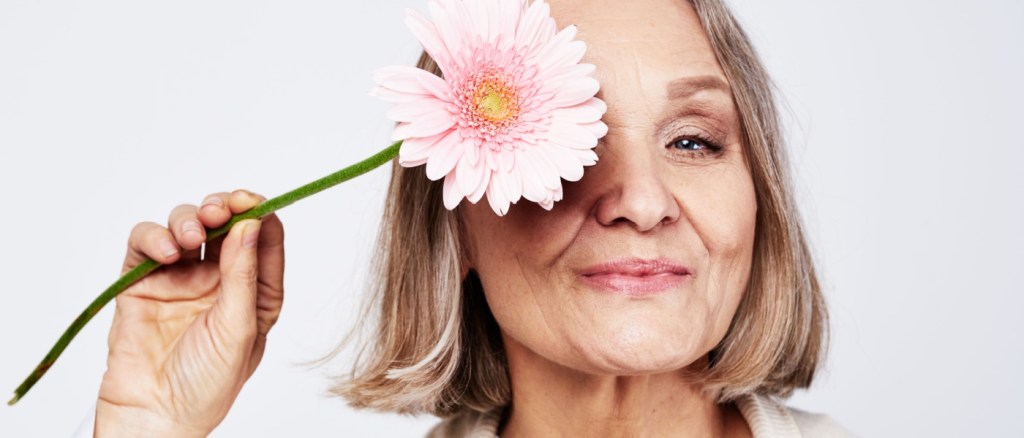 Donna anziana con un fiore davanti l'occhio