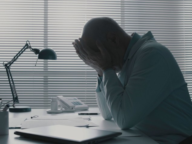 Lavoratore con mani sul viso ad una scrivania