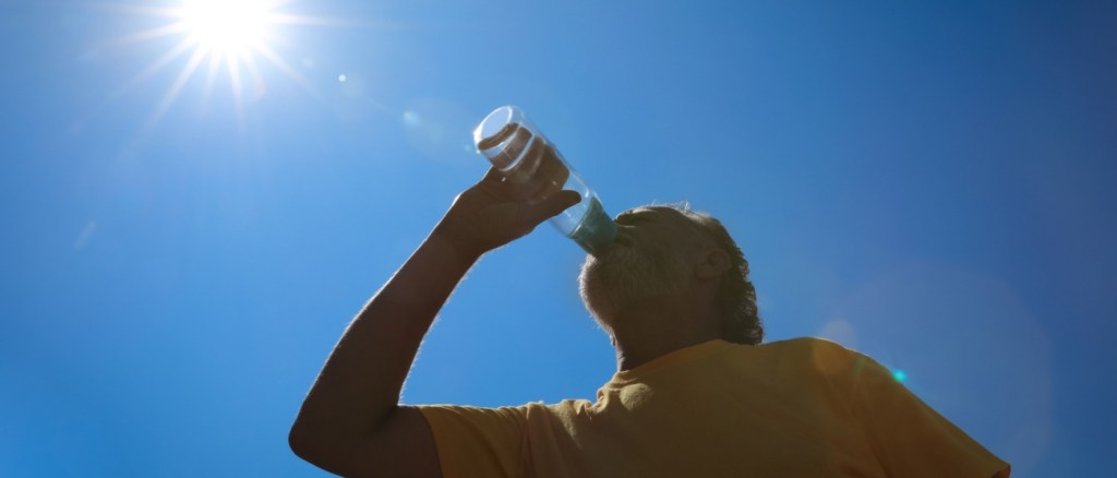 foto in controluce di uomo che beve acqua da una bottiglietta