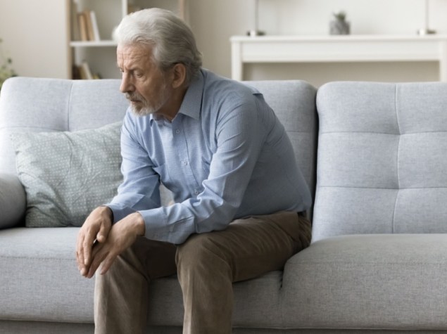 Uomo anziano solo, seduto su un divano