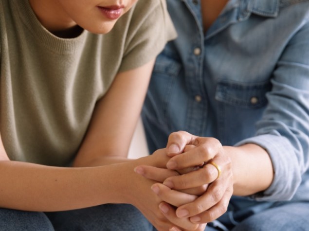 Giovane ragazza seduta sul divano a fianco ad un adulto che la tiene per mano