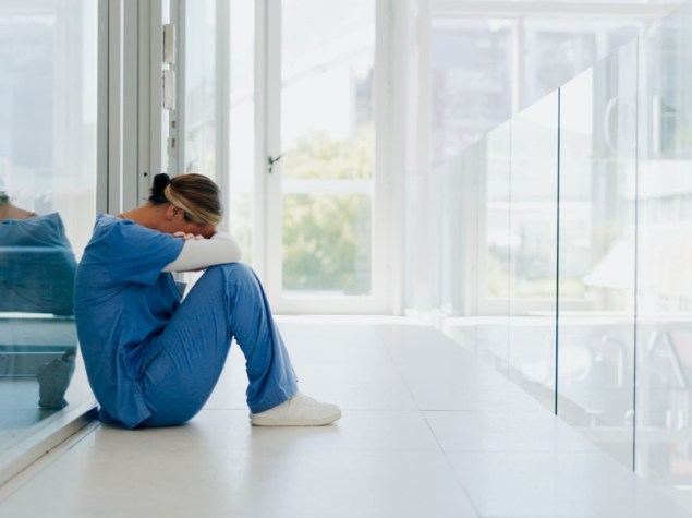 Donna medico seduta a terra con capo chino