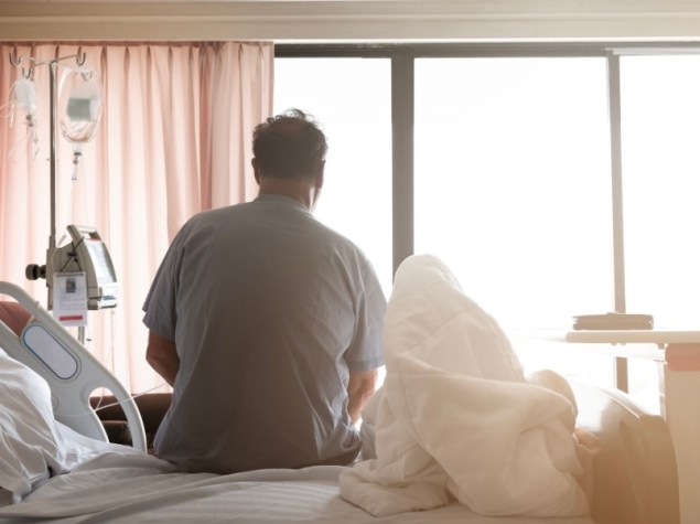 Uomo seduto di spalle su letto di ospedale