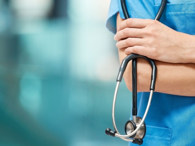 dottore in camice con le braccia conserte e lo stetoscopio nella mano sinistra